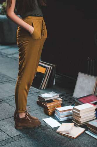 mujer parada frente a libros en el piso