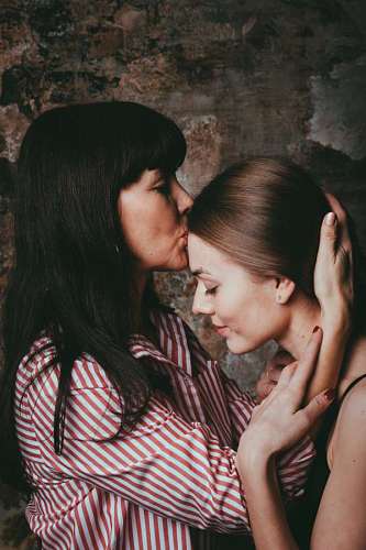besos una madre besando a su hija con una pared derruida de fondo