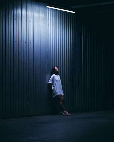 Mujer joven posando frente a una pared iluminada en la noche