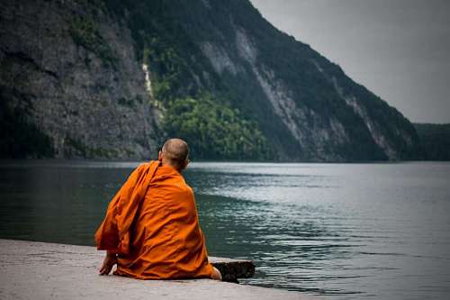 conocimiento Monje Budista meditando frente a un lago