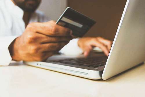 Hombre comprando desde la computadora con tarjeta de credito por internet
