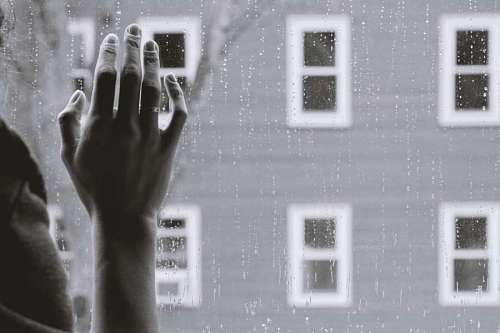 blanco y negro Mano de mujer en la ventana mientras llueve