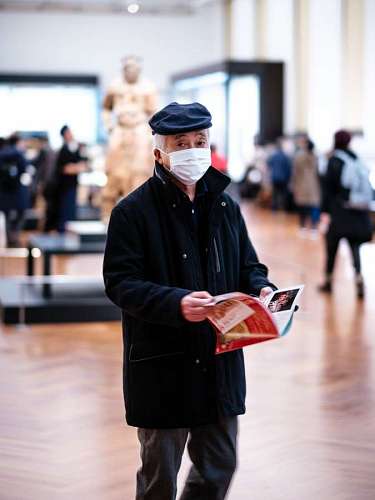 cuidado de la salud hombre con protección sosteniendo una revista parado en medio de un museo
