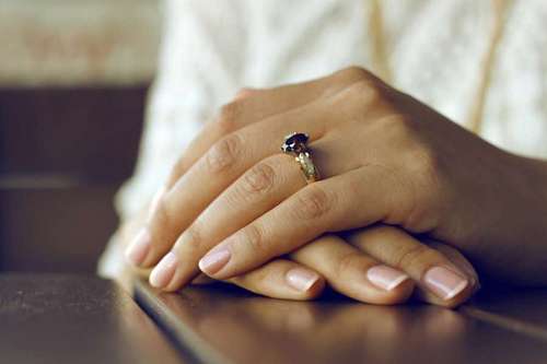 doblado Manos de mujer con anillo de compromiso 