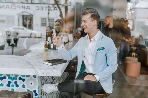 cafeteria hombre sentado en una cafetería con su celular a través de la vidriera