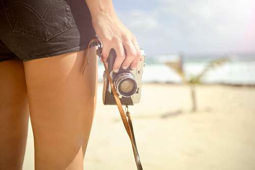 pantalones cortos Mujer en la playa con camara fotografica