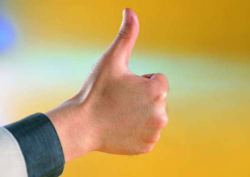 primer plano de una mano levantando el pulgar con un fondo amarillo