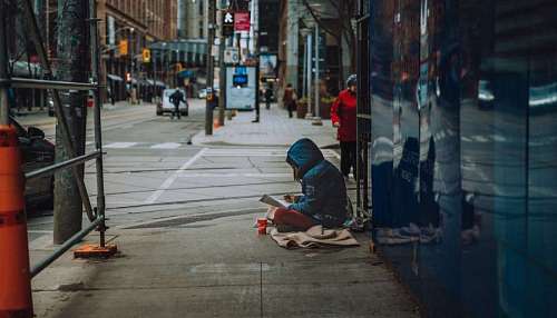 tristeza persona indigente sentada en la calle leyendo un diario