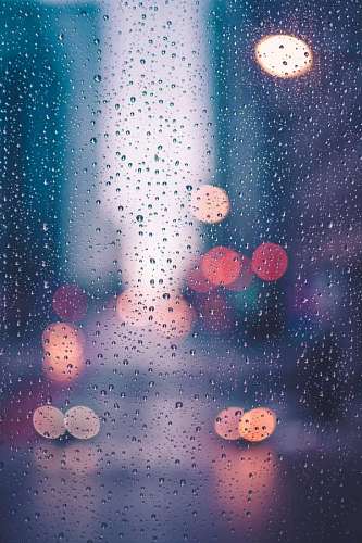 Gotas de lluvia en una ventana con luces de cuidad de fondo
