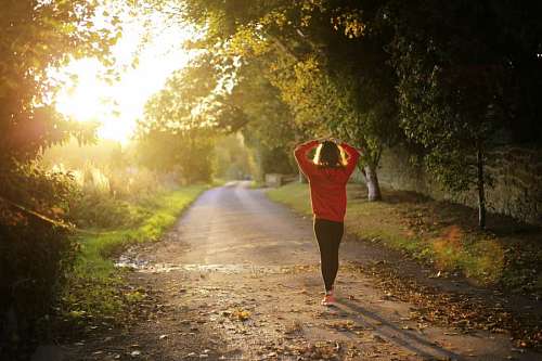 marcha mujer caminando sola por la carretera con el sol enfrentado