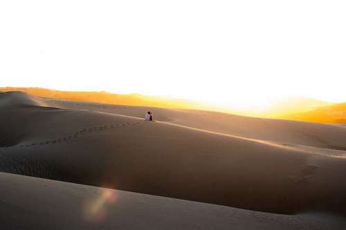 excursionista Mujer sentada en una duna del desierto en solitario