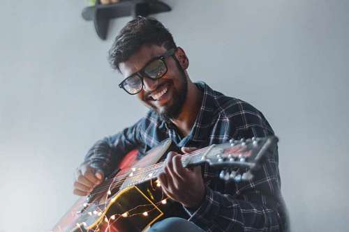 tocar hombre con gafas tocando la guitarra