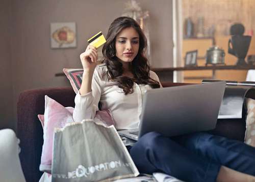 Mujer en el sofa comprando con tarjeta de credito en su laptop