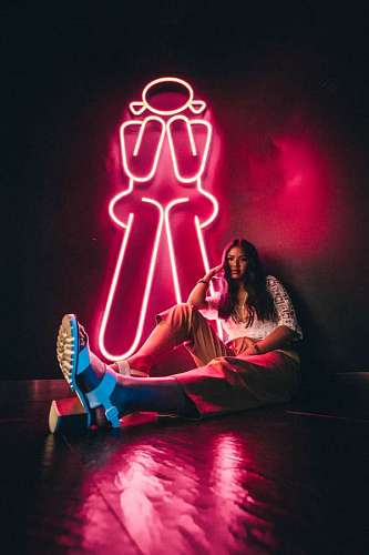 femenino Mujer joven posando sentada junto a un cartel luminoso