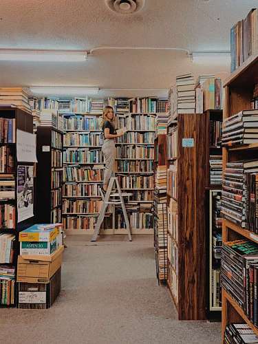 mujer acomodando libros en el fondo de la biblioteca
