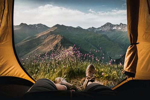 zapatos Hombre mirando paisaje con flores desde su tienda de campaña
