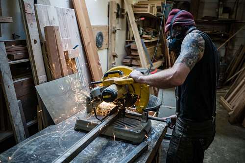 tecnico Trabajador cortando metal con una sierra en el taller
