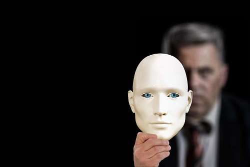 misterio primer plano de una máscara sostenida por hombre de detrás con fondo de estudio negro