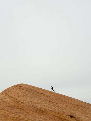 hombre corriendo hacia la cima de una colina de arena