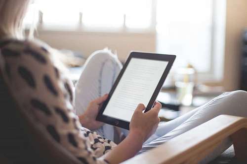 en linea Mujer joven sentada leyendo un ebook en una tablet 