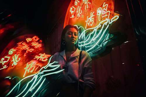 letrero Mujer mirando a la camara con fondo de luces de neon en la noche