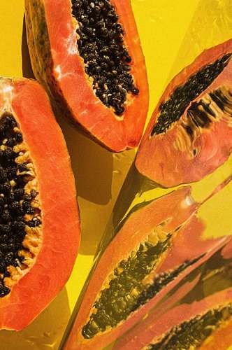 Papayas cortadas al medio sobre fondo amarillo