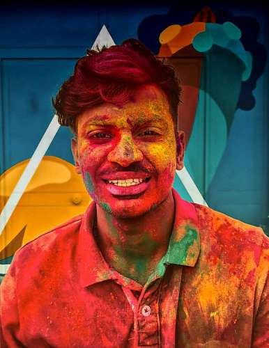 cubierto hombre sonriendo para la cámara cubierto de polvo de colores
