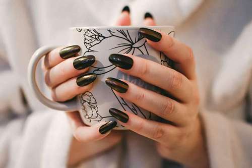 8 Mujer con manicura negra con taza de cerámica floral blanca y gris