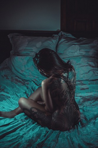 mistico Mujer desnuda con tatuajes recostada sobre la cama 