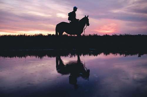 valle Hombre cabalgando al atardecer frente aun rio en el campo