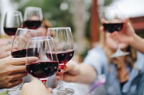 Grupos de personas brindando con copas de vino en un festejo
