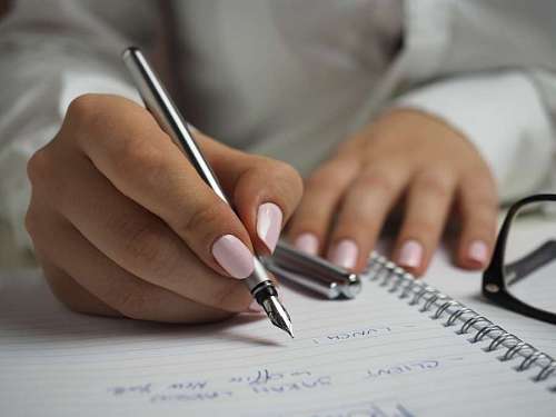 clave Mujer en camisa de manga larga blanca con una pluma de escritura en un papel