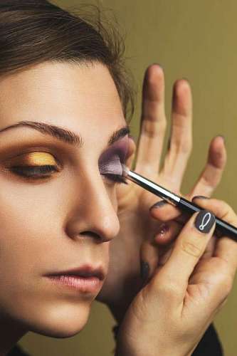 mascarada primer de mujer maquillándose con un fondo beige