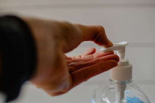 bombo mujer esparciendo alcohol en gel sobre su mano