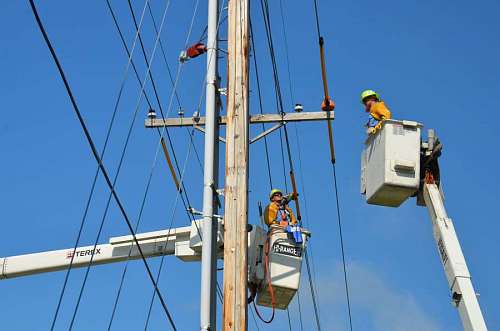 dos obreros colocando cables de alta tensión