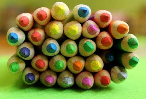 Lapices de colores apilados sobre fondo verde