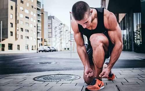 entrenamiento hombre fitness atándose los cordones en la calle