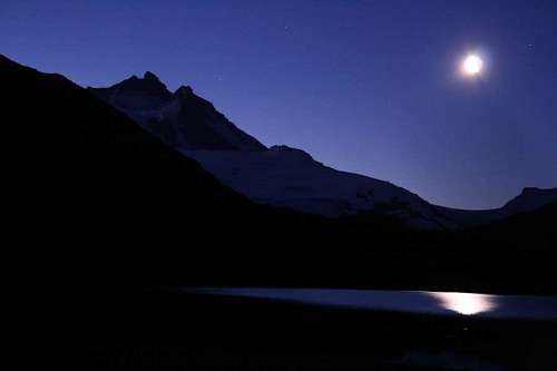 Luna reflejando al anochecer sobre un lago de montaña