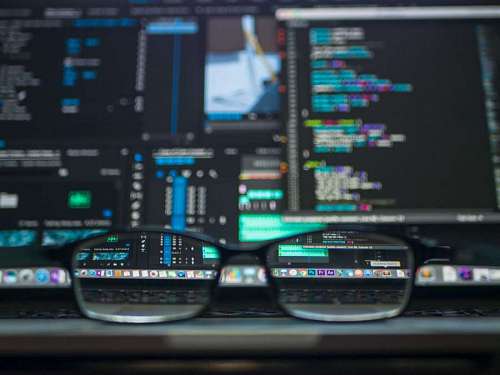 pc primer plano de gafas frente a un monitor con codigos