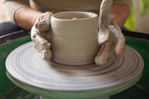 Mujer haciendo un jarro de ceramica en el torno con arcilla fresca