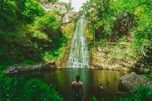 Hombre parado frente a una cascada en Hawai