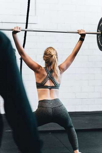 entrenamiento Mujer joven de espaldas en el gimnasio levando pesas