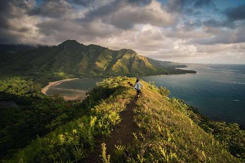 Mujer caminando en la cima de una montaña frente al mar