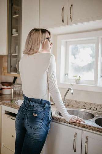 internet Mujer joven mirando por la ventana en la cocina