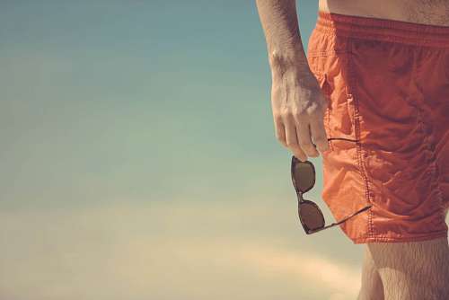 pantalones cortos Hombre con lentes de sol en la playa