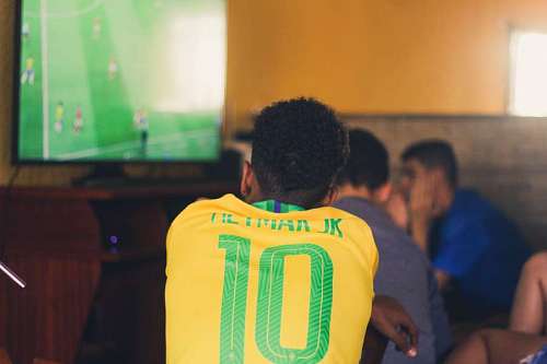 television Hombre vestido con camiseta de fútbol brasileño viendo television